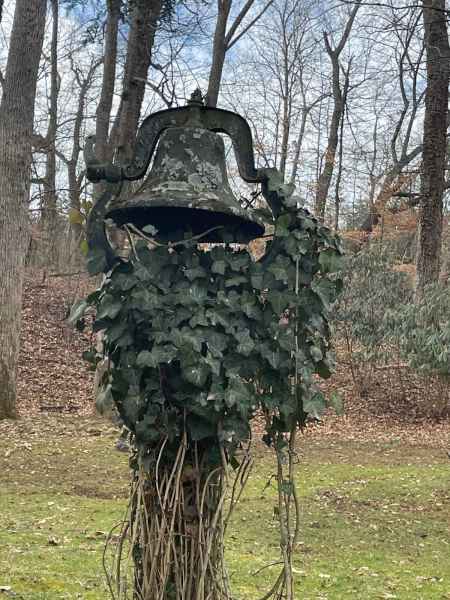 Bell on post overgrown with ivy